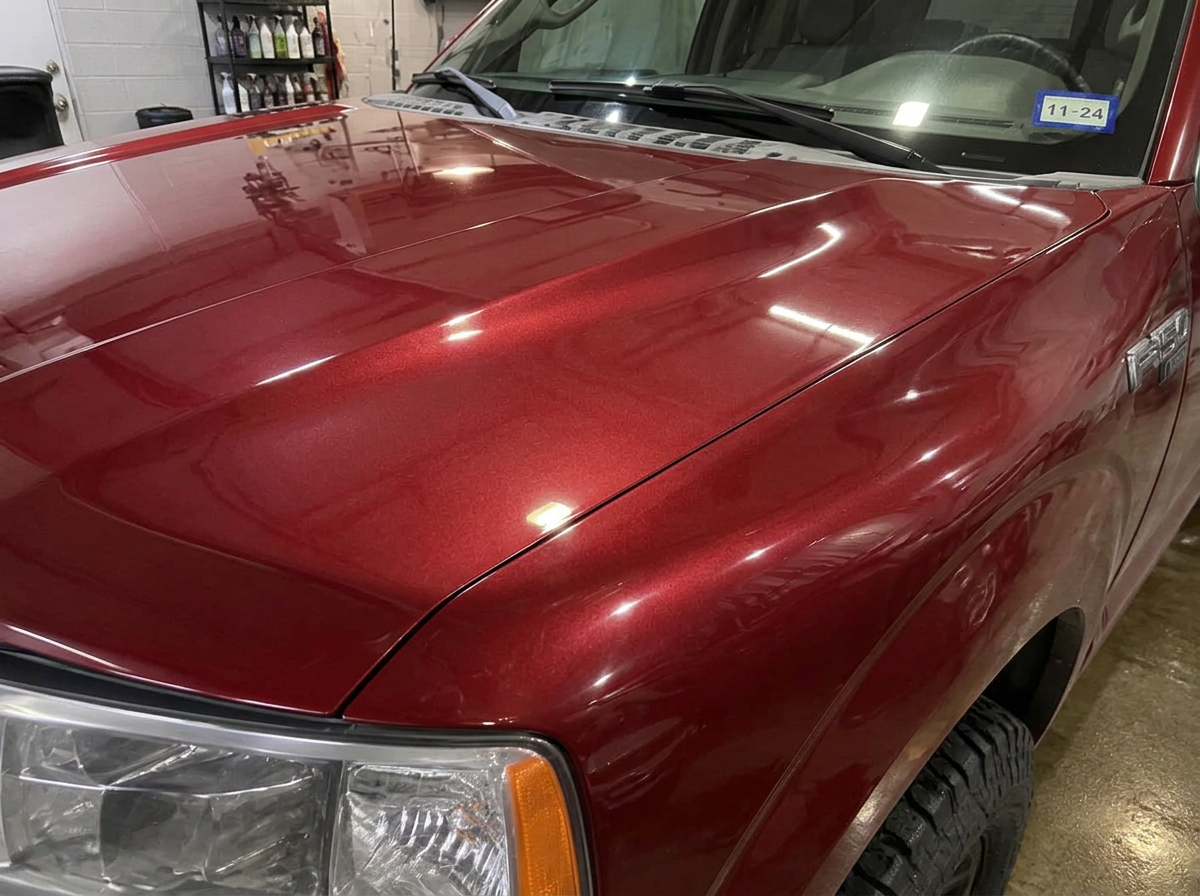 Same dark red pickup hood after ceramic coating with deep candy-like gloss