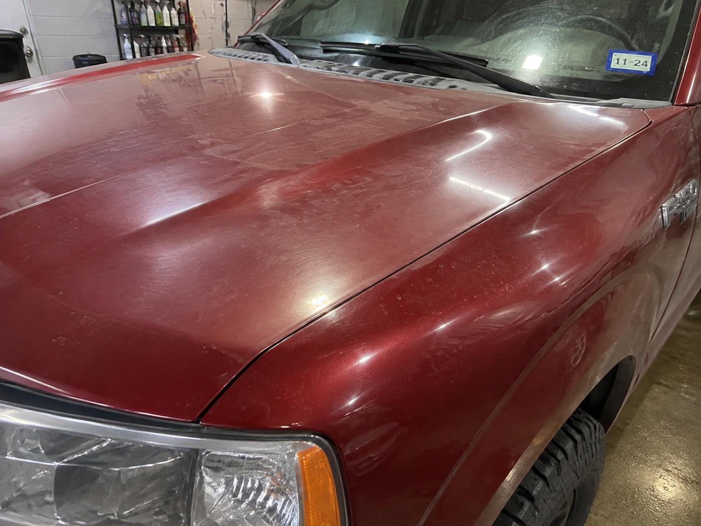Dark red pickup hood before ceramic coating looking flat with water spots