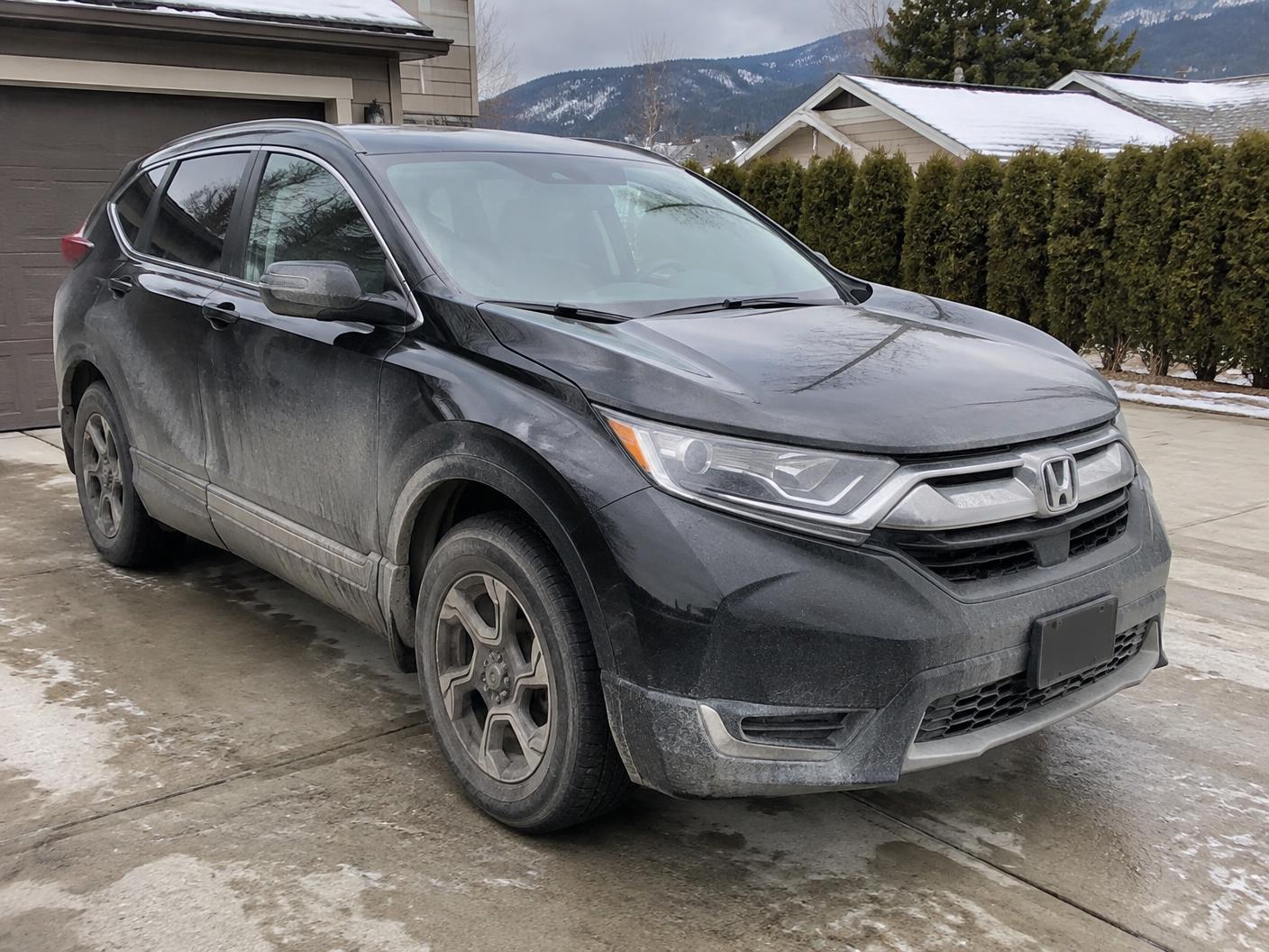 Black SUV before exterior detailing with winter road film, salt and dirty wheels