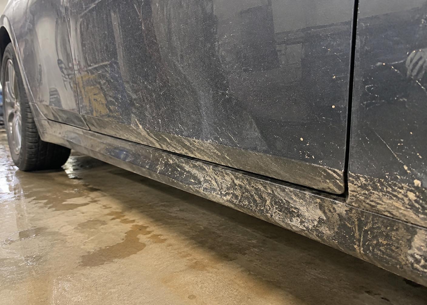 Road film and mud on a vehicle lower door before detailing