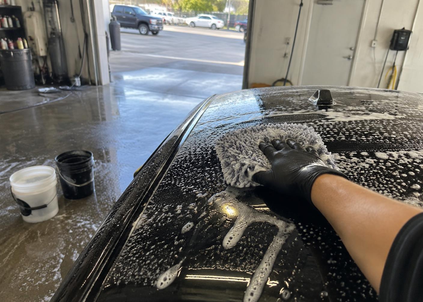 Foamed black vehicle hand washed with a microfiber mitt