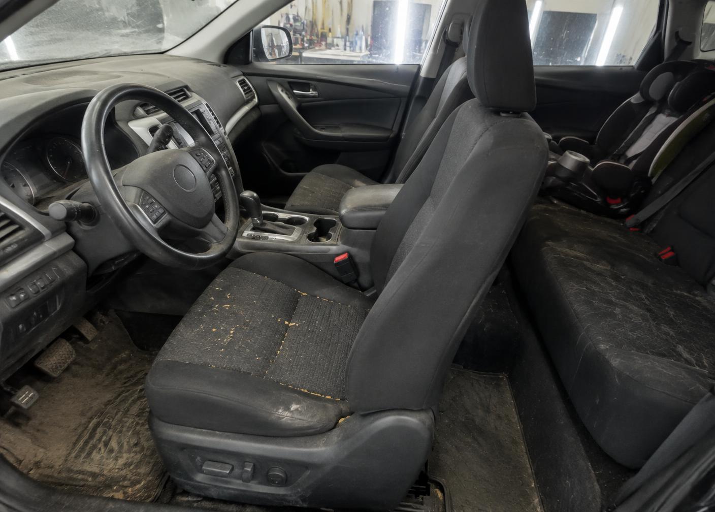Vehicle interior before detailing with stained mats and dusty dashboard