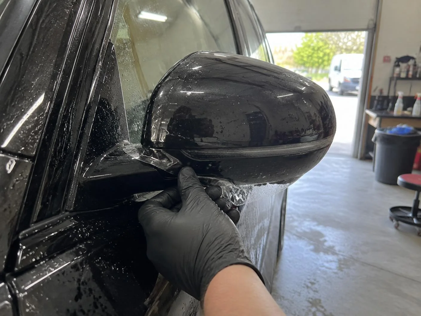 Protection film edge being tucked around a wing mirror