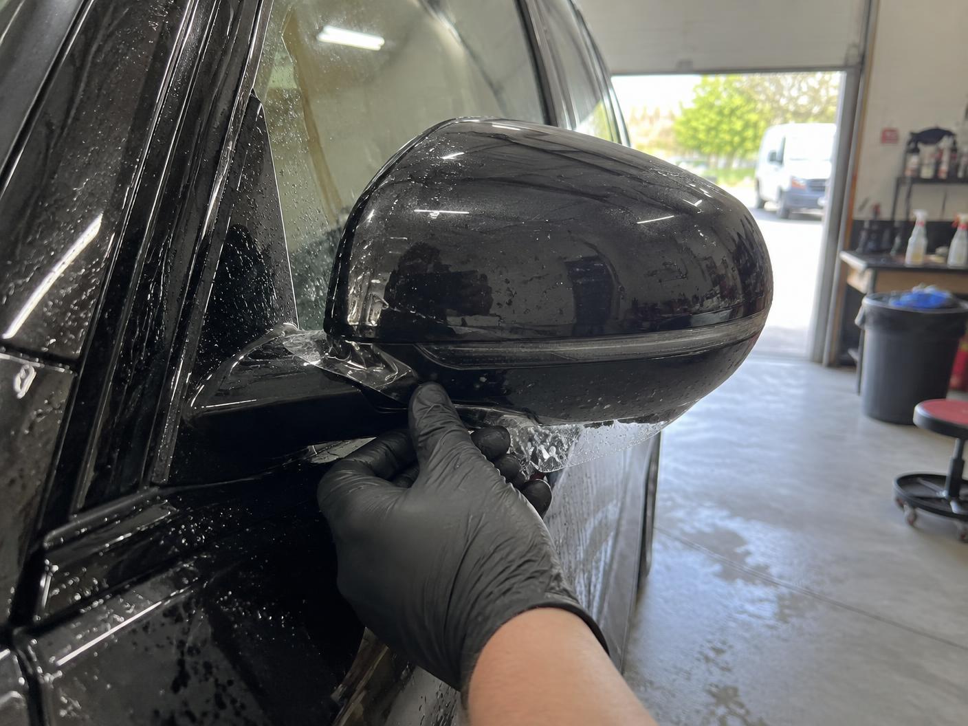 Protection film edge being tucked around a wing mirror