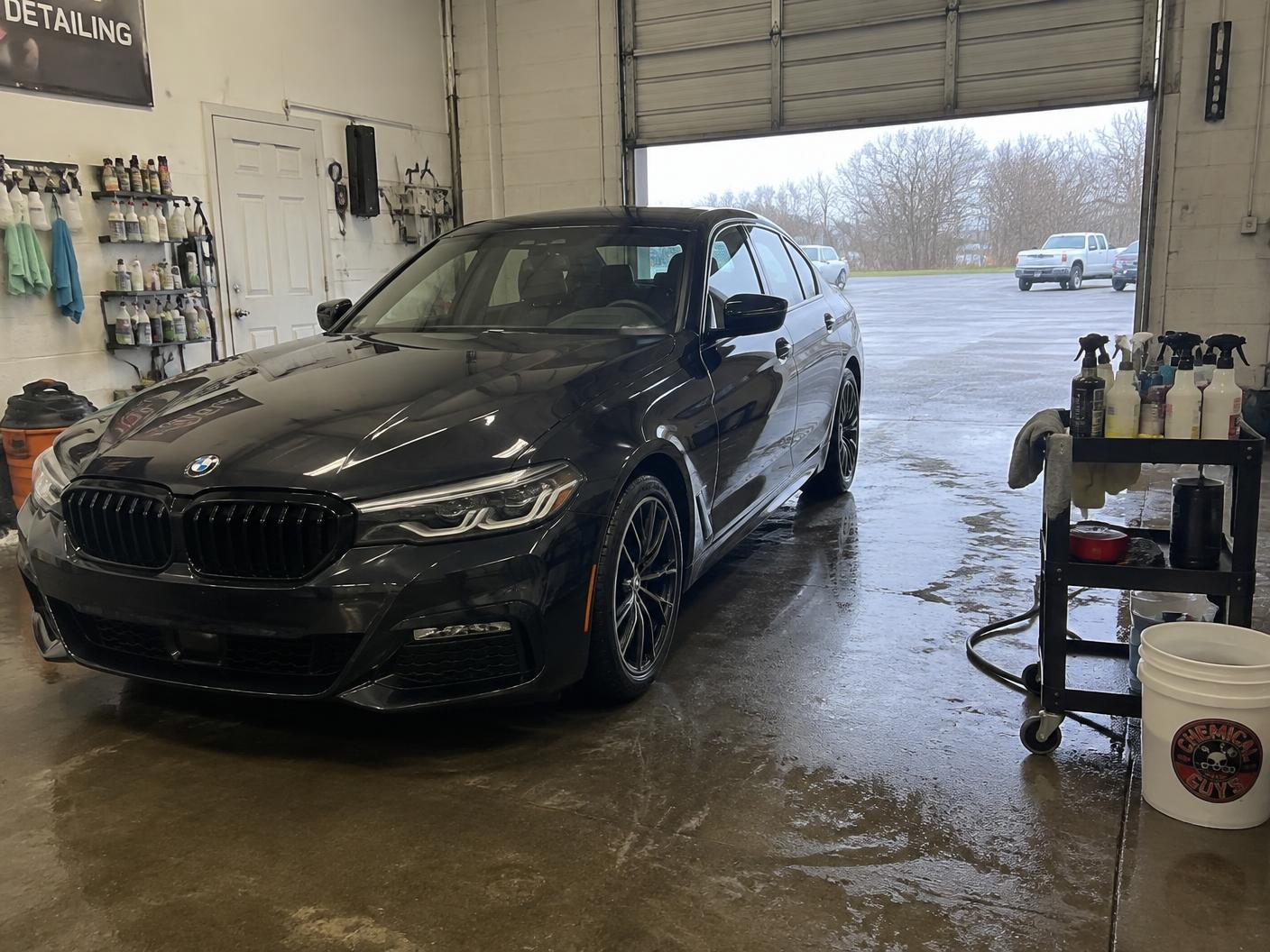 Clean dark sedan in the shop bay at the end of a detail